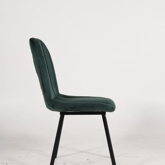 Silla de comedor de terciopelo verde con patas de hierro en comedor elegante
